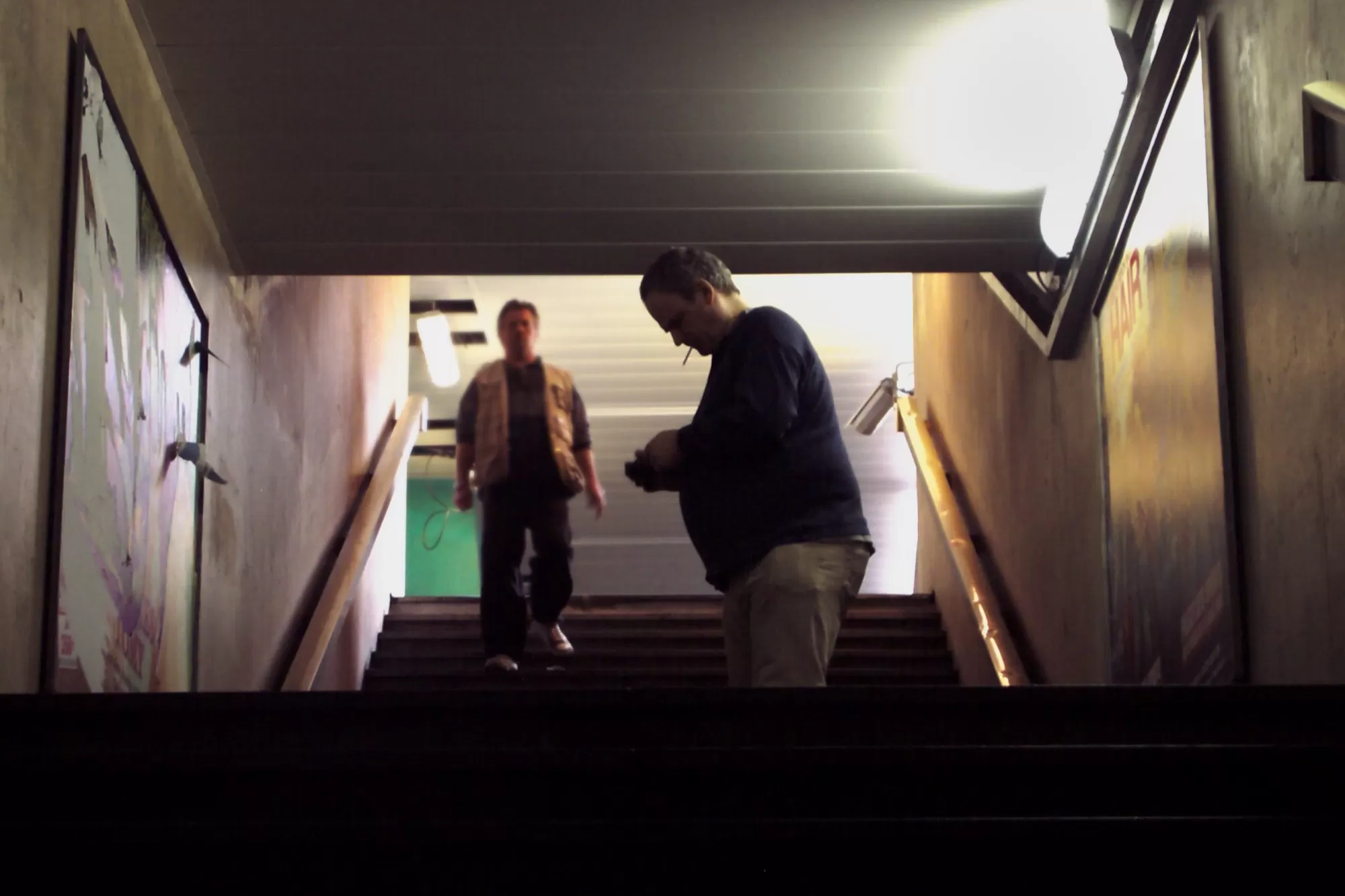 Philippe De Jonckheere photographiant une affiche déchirée dans un escalier du métro parisien
